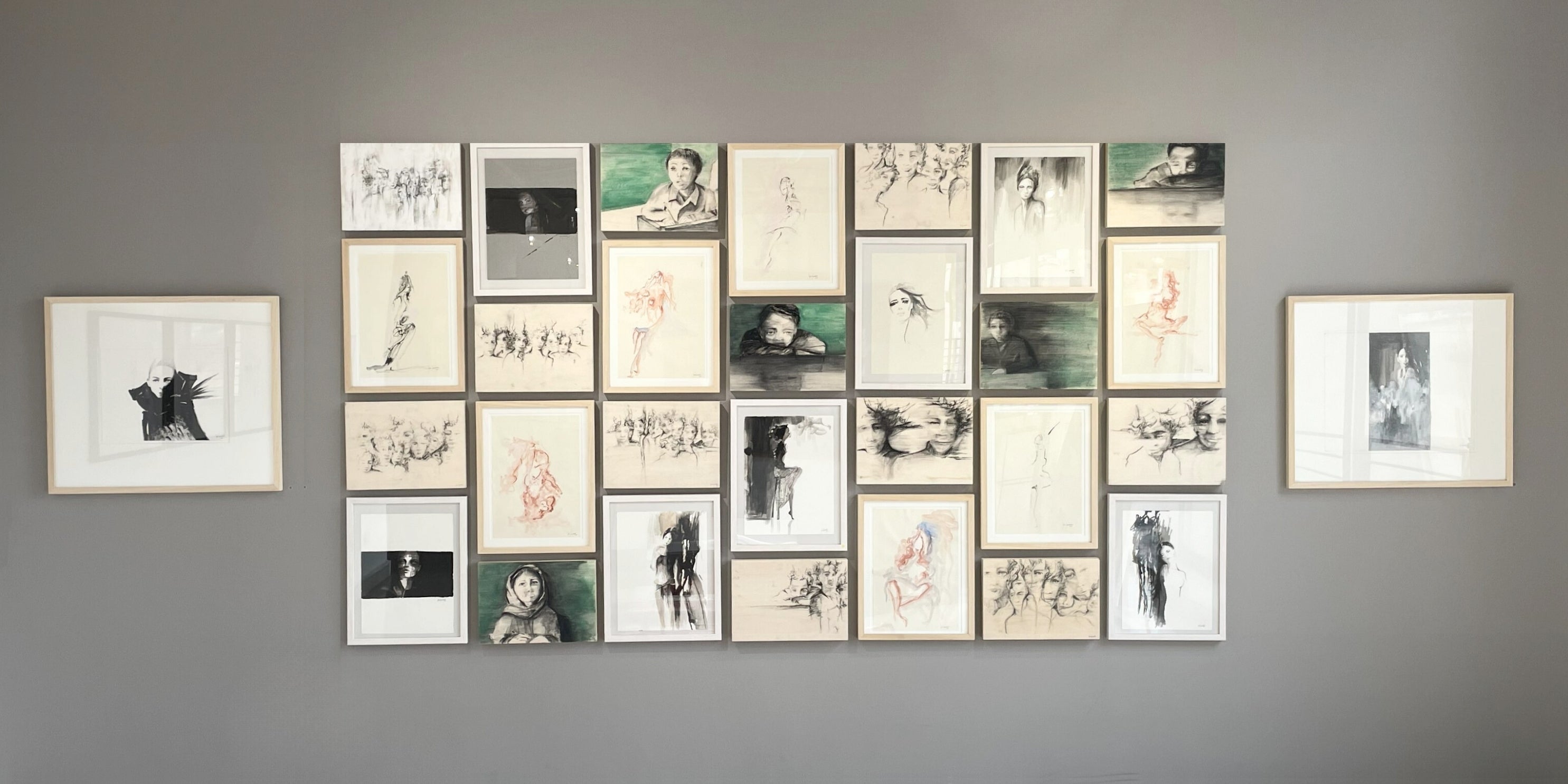 Collage of framed artworks on a gray wall by Rita Rawashdeh